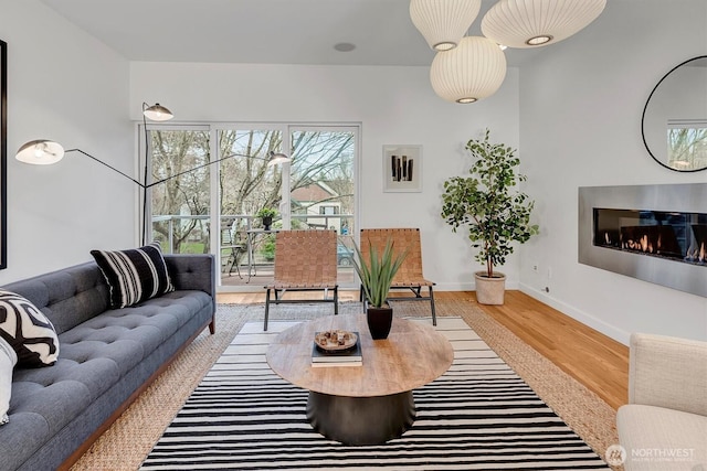 living room with baseboards, wood finished floors, and a glass covered fireplace