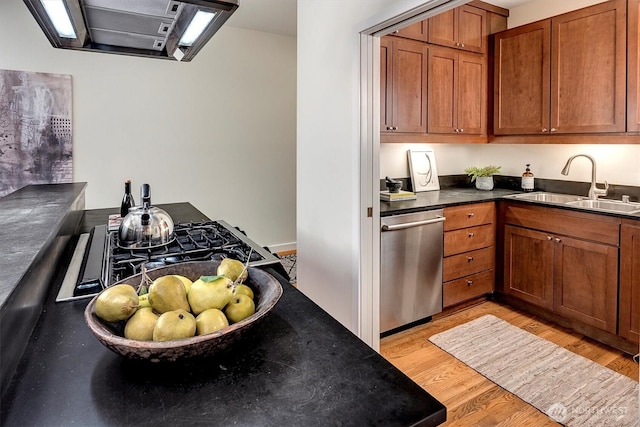 kitchen with brown cabinetry, dark countertops, light wood-type flooring, stainless steel dishwasher, and a sink