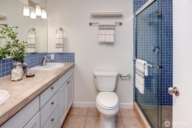 bathroom featuring toilet, a sink, tile patterned floors, tasteful backsplash, and a stall shower