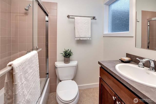 bathroom with baseboards, shower / bath combination with glass door, vanity, and toilet