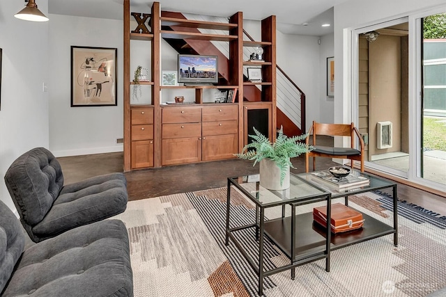 living area with concrete flooring, plenty of natural light, stairs, and baseboards