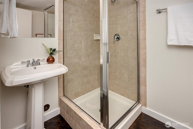 full bath featuring a stall shower and baseboards