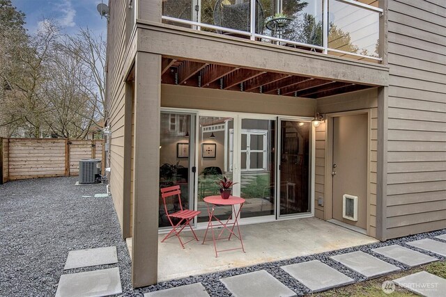 exterior space with central AC unit, a balcony, heating unit, fence, and a patio area