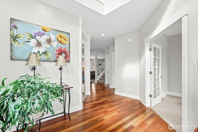 hallway with stairs, baseboards, and wood finished floors