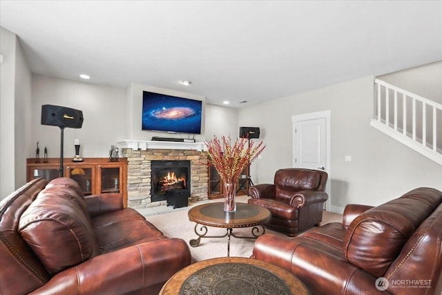 living room featuring a stone fireplace, stairs, and recessed lighting