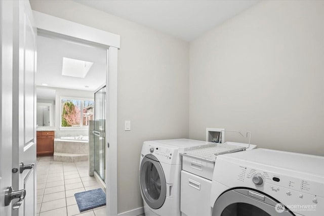 laundry area featuring washing machine and clothes dryer, laundry area, a skylight, and light tile patterned floors