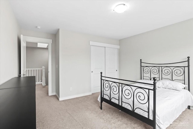 bedroom featuring light colored carpet, a closet, and baseboards