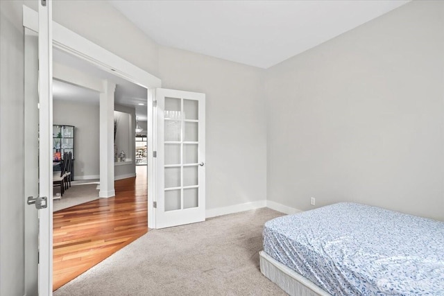 carpeted bedroom with french doors and baseboards