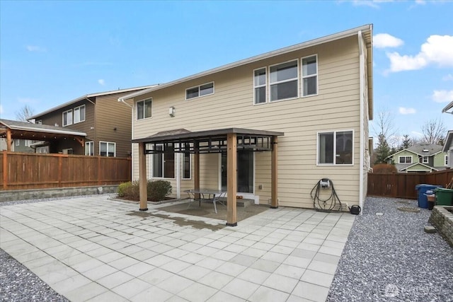 rear view of property featuring a gazebo, fence, and a patio area