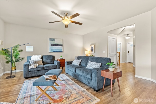 living area with light wood-style floors, baseboards, and a ceiling fan