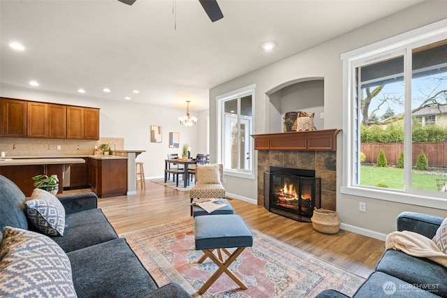 living area with light wood-type flooring, recessed lighting, baseboards, and a tile fireplace