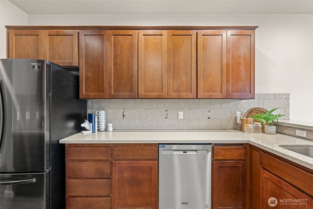 kitchen with appliances with stainless steel finishes, brown cabinetry, light stone countertops, and decorative backsplash