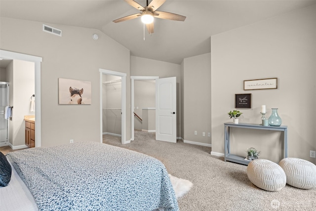 bedroom with baseboards, visible vents, light colored carpet, lofted ceiling, and a walk in closet