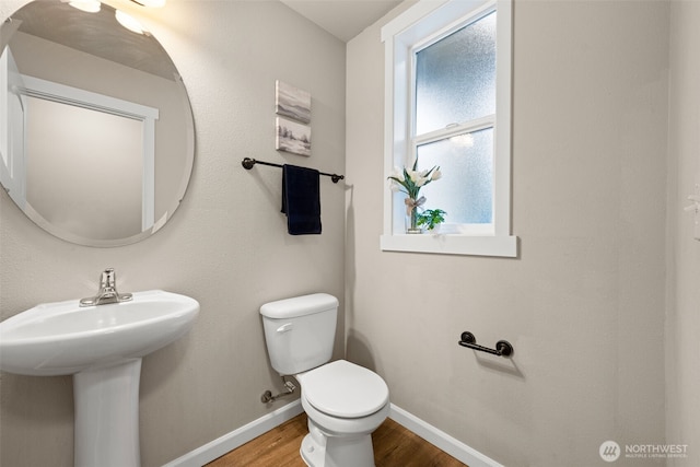 bathroom featuring a sink, wood finished floors, toilet, and baseboards