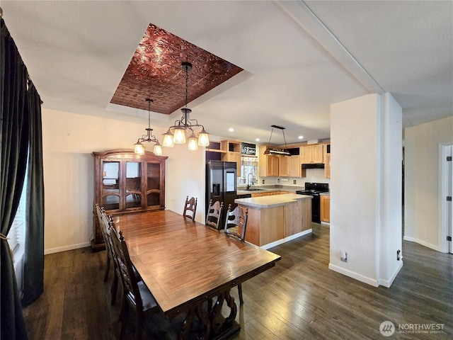 dining room with a tray ceiling, dark wood-style flooring, baseboards, and recessed lighting