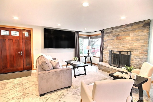 living area with marble finish floor, a stone fireplace, and recessed lighting