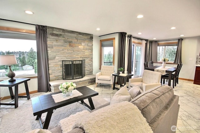 living area featuring recessed lighting, a stone fireplace, and baseboards