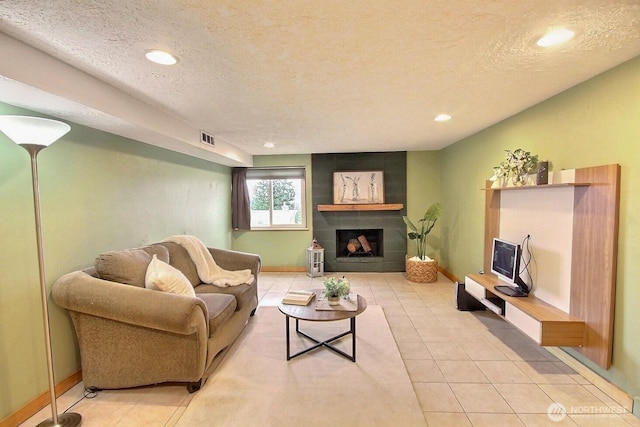 living room with tile patterned floors, visible vents, a textured ceiling, and a tile fireplace