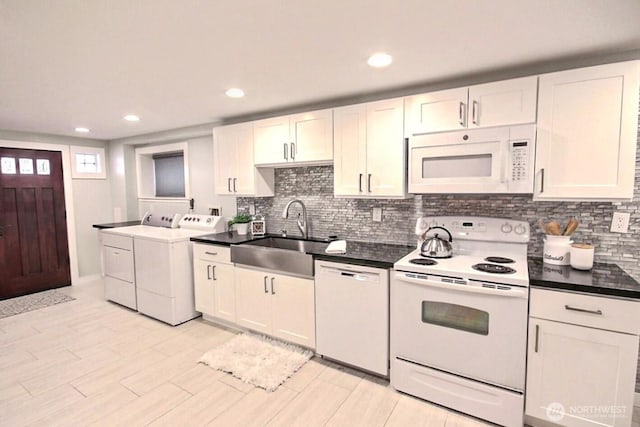 kitchen with separate washer and dryer, white appliances, a sink, white cabinets, and dark countertops