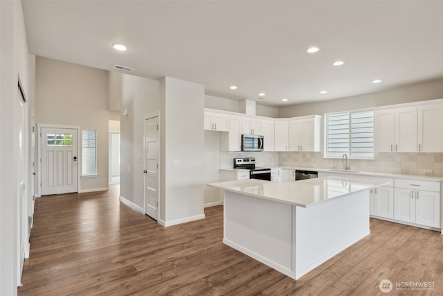 kitchen with visible vents, appliances with stainless steel finishes, a kitchen island, and white cabinetry