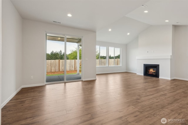 unfurnished living room with recessed lighting, visible vents, a glass covered fireplace, vaulted ceiling, and wood finished floors