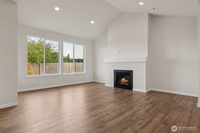 unfurnished living room with recessed lighting, wood finished floors, baseboards, vaulted ceiling, and a glass covered fireplace