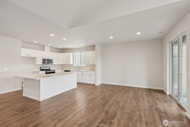 kitchen featuring a kitchen island, appliances with stainless steel finishes, light countertops, white cabinetry, and a sink