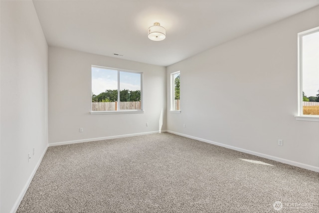 empty room with carpet, visible vents, and baseboards