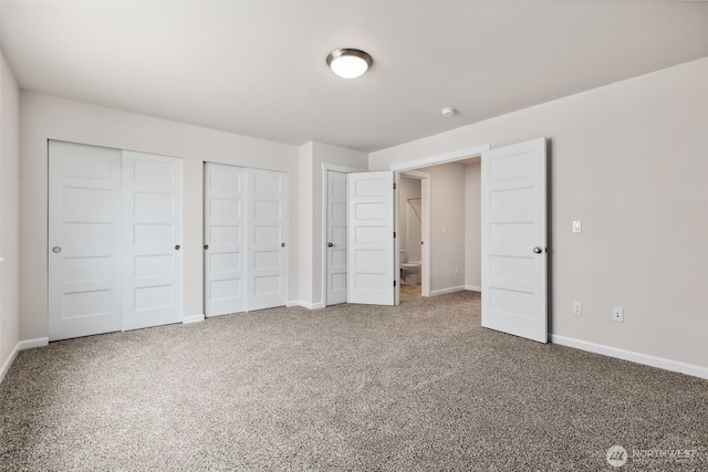 unfurnished bedroom with carpet, two closets, and baseboards