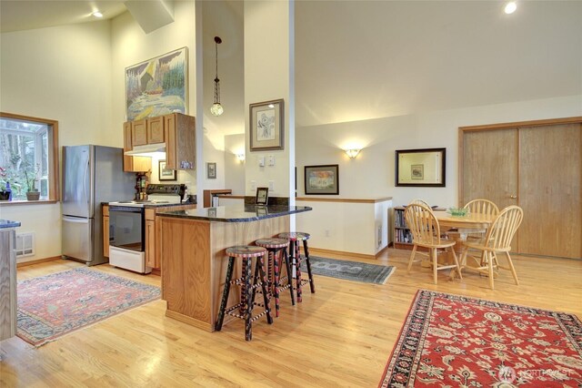 16 Koala Ln, Pacific Beach, WA 98571 - kitchen featuring range with electric stovetop, high vaulted ceiling, light wood-style flooring, a kitchen bar, and recessed lighting