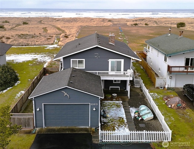 view of front facade with fence private yard, a water view, driveway, and an attached garage