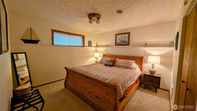 bedroom featuring light carpet, a textured ceiling, visible vents, and baseboards