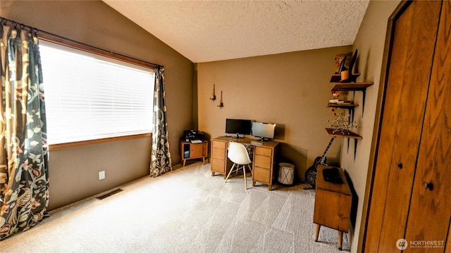 home office with visible vents, vaulted ceiling, a textured ceiling, and light colored carpet