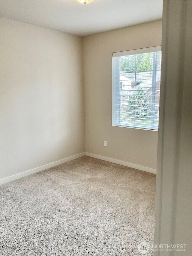 carpeted empty room featuring baseboards