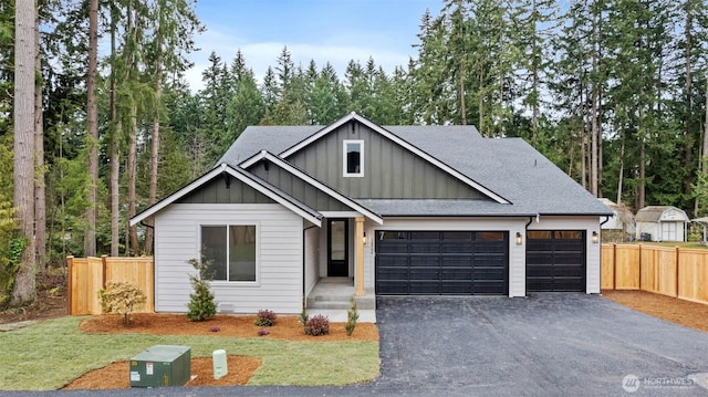 view of front facade featuring driveway, a shingled roof, fence, and board and batten siding