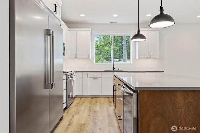 kitchen with stainless steel appliances, pendant lighting, white cabinets, and a sink