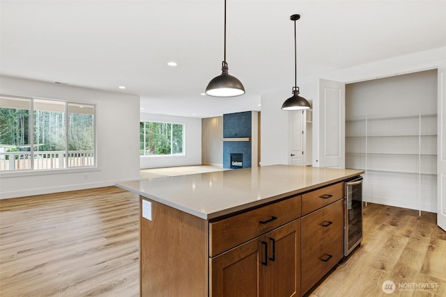 kitchen featuring a center island, light countertops, hanging light fixtures, brown cabinetry, and open floor plan