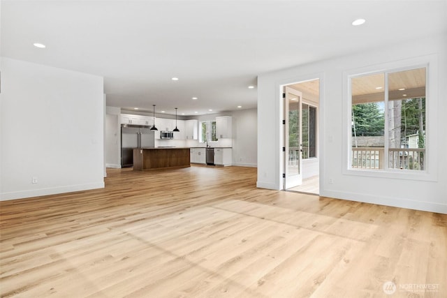 unfurnished living room with light wood-type flooring, baseboards, and recessed lighting