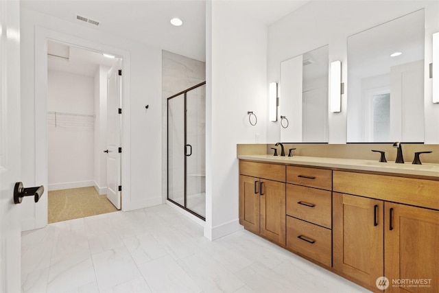 bathroom featuring a spacious closet, a sink, visible vents, and a shower stall