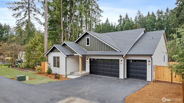 view of front facade featuring a garage, a shingled roof, fence, driveway, and board and batten siding