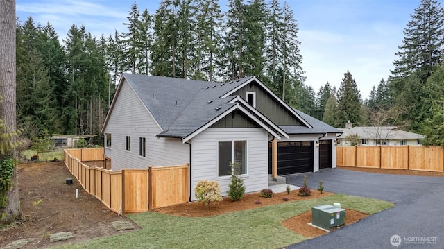 view of front facade featuring driveway, an attached garage, fence, and board and batten siding