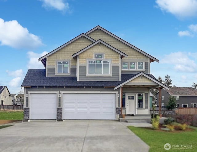 craftsman-style home with an attached garage, a shingled roof, driveway, and fence