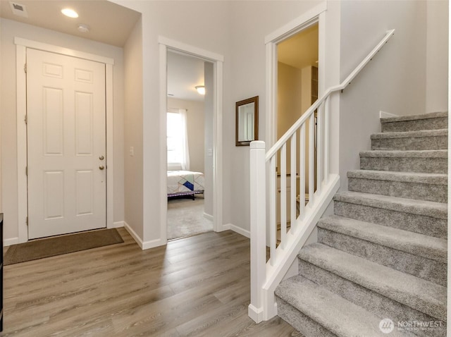 foyer with visible vents, stairway, baseboards, and wood finished floors