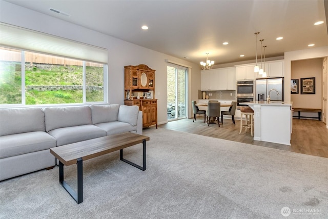 living room with light wood-type flooring, visible vents, a chandelier, and recessed lighting