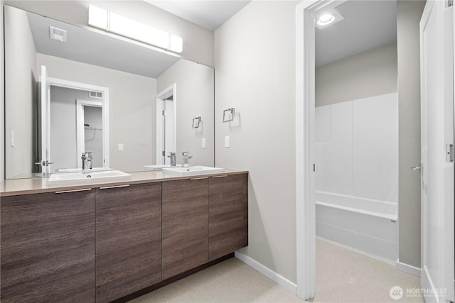 full bath featuring double vanity, baseboards, visible vents, and a sink