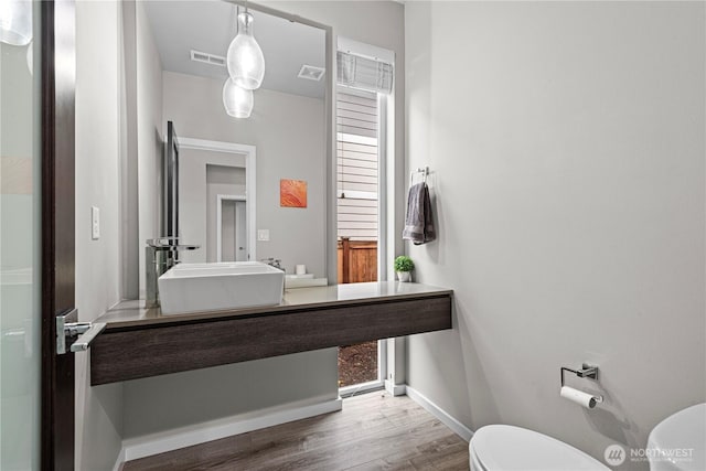 bathroom featuring baseboards, visible vents, toilet, and wood finished floors