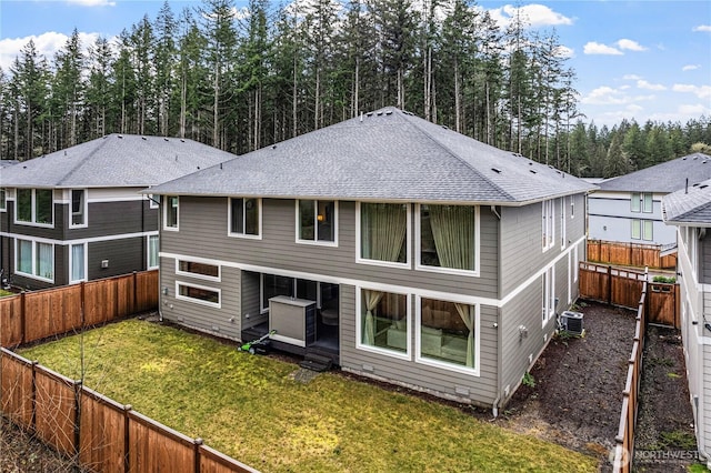 rear view of property with a shingled roof, a fenced backyard, a lawn, and central AC unit