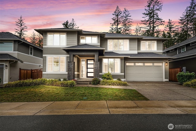 prairie-style home featuring driveway, roof with shingles, an attached garage, and fence