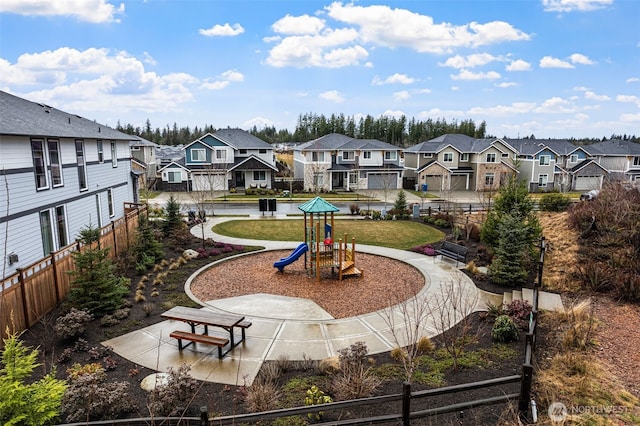 view of home's community with playground community, a lawn, fence, and a residential view