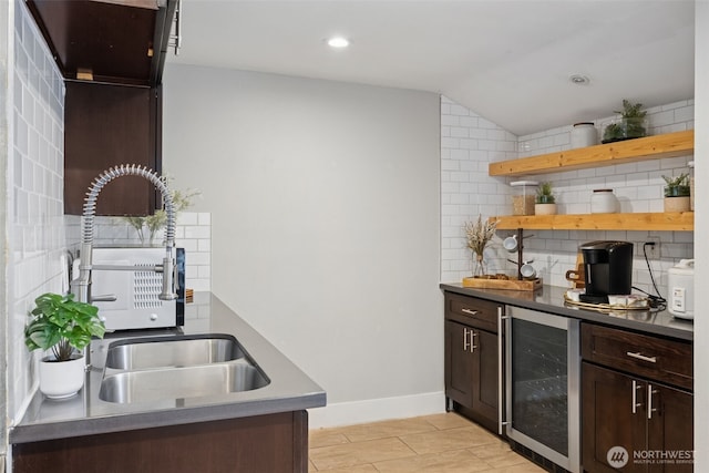 bar featuring wine cooler, backsplash, vaulted ceiling, a sink, and baseboards